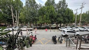A parking area with multiple cars and motorcycles, surrounded by trees and potted plants. - Kuqa Haodu Business Hotel (Kuqa)