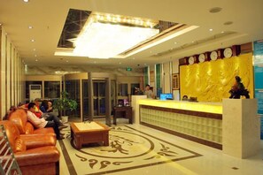 A hotel lobby with a reception desk, seating area, and a large chandelier. - Kuqa Haodu Business Hotel (Kuqa)