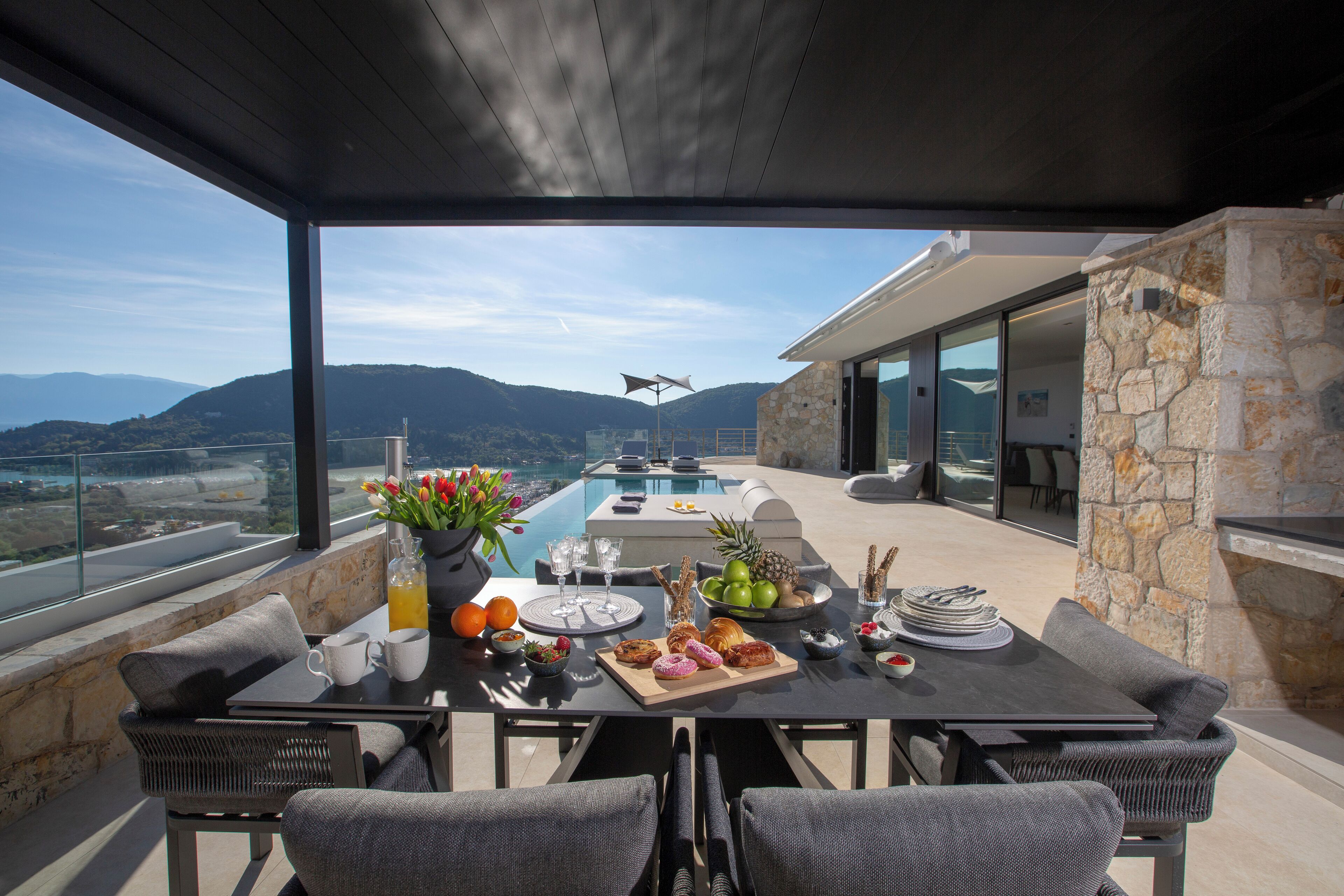 Ein Essbereich mit Tisch für vier Personen, mit Blick auf einen Pool und Berge.