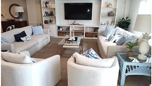 Een woonkamer met twee banken, een salontafel, een televisie en planken met decoratieve objecten.