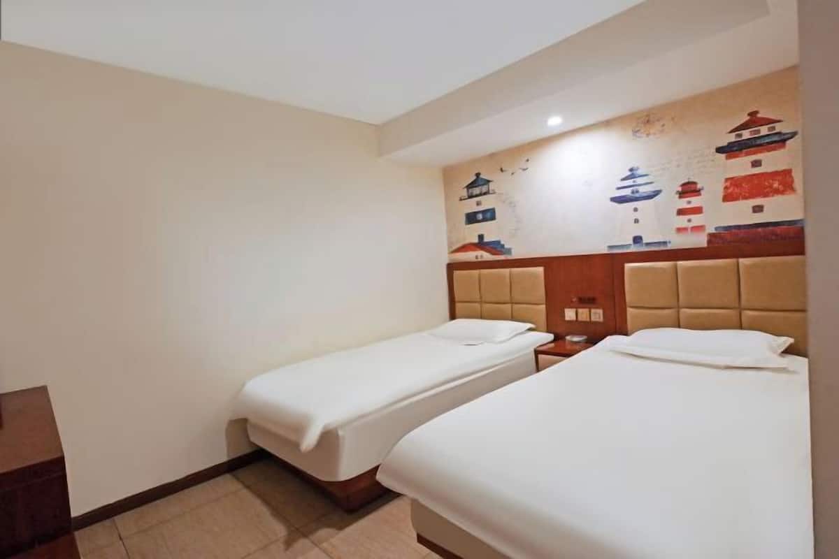 A hotel room with two single beds, a wooden headboard, and a wall mural of traditional buildings.