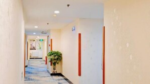 A hotel corridor with a patterned carpet, a potted plant, and a sign on the wall. - Super 8 Hotel (Beijing Jianguomen Subway Station Capital Children's Research Institute) (Beijing)