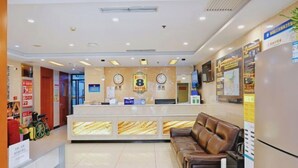 A hotel reception area with a reception desk, two clocks, a sofa, and a refrigerator. - Super 8 Hotel (Beijing Jianguomen Subway Station Capital Children's Research Institute) (Beijing)