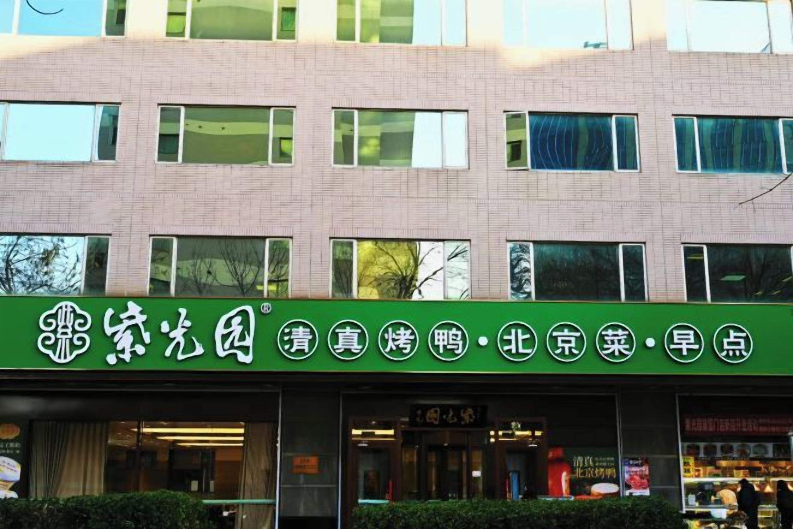 A building with a green signboard displaying Chinese characters, windows, and a visible entrance.