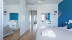A modern bedroom with a large bed, two bedside tables, a mirror, and artwork on the walls. - Between sea and city, 15 minutes from the airport, 5 minutes from the excavations of Ostia Antina, (Lazio)