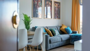A modern living room with a grey sofa, white chairs, and a dining table. There are three framed animal paintings on the wall. - Between sea and city, 15 minutes from the airport, 5 minutes from the excavations of Ostia Antina, (Lazio)
