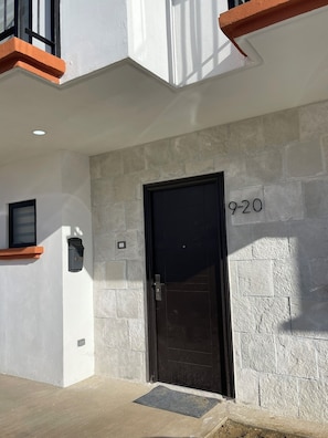 Enter unit 9-20 through the black door, flanked by a small window and a mailbox.