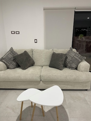 Relax in this stylish living room with a comfortable sofa, coffee table, and large window offering a view of the outside.