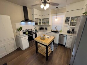 A modern kitchen with white cabinets, a wooden table, and stainless steel appliances.