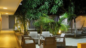 A covered outdoor seating area with wicker furniture and potted plants. - Hotel Rodadero Beach Blue (Santa Marta)