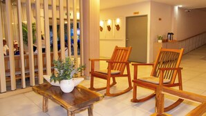 A lobby with wooden furniture, a potted plant, and a door in the background. - Hotel Rodadero Beach Blue (Santa Marta)