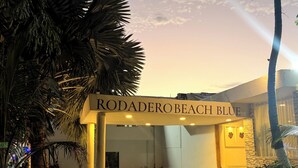 The entrance of Rodadero Beach Blue with a sign, palm trees, and a pathway leading to the building. - Hotel Rodadero Beach Blue (Santa Marta)