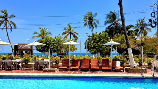 A poolside area with lounge chairs, umbrellas, and a café named 'CAFÉ D'APRAIA.' - Hotel Rodadero Beach Blue (Santa Marta)