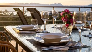 Une table dressée pour le dîner, avec une vue sur la mer et les montagnes en arrière-plan.