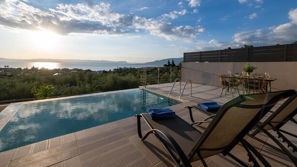 Une piscine sur le toit offrant une vue sur la mer et les montagnes, des chaises longues et une table avec des chaises.