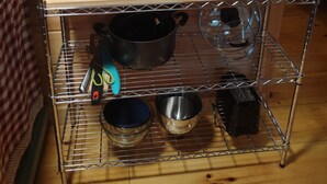 A kitchen shelf with various utensils, a fire extinguisher, and cookware. - Pine Ridge Cabin - A Cozy Getaway for Two near Jasper AR! (Jasper)