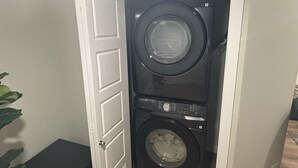 A compact laundry room with a front-loading washer and dryer. - The Snug Spot,Retreat offers a warm and inviting escape for travelers. (Winnipeg)
