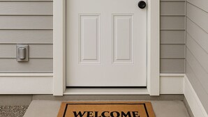 A white front door with a doormat that reads "WELCOME". - The Snug Spot,Retreat offers a warm and inviting escape for travelers. (Winnipeg)