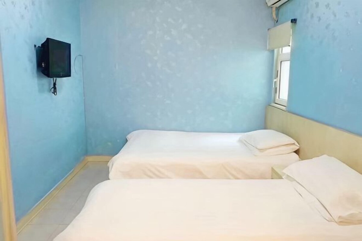 Een kamer met twee bedden, een televisie aan de muur en een raam.