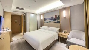 A hotel room with a bed, a desk with a telephone, a chair, and a painting on the wall. - Vienna Classic Hotel (Nanjing Nanzhan Jiangning Wanda Plaza) (Nanjing)