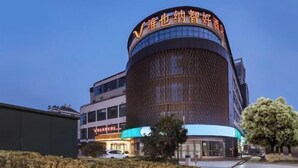 A modern building with a curved facade and illuminated signage. - Vienna Classic Hotel (Nanjing Nanzhan Jiangning Wanda Plaza) (Nanjing)