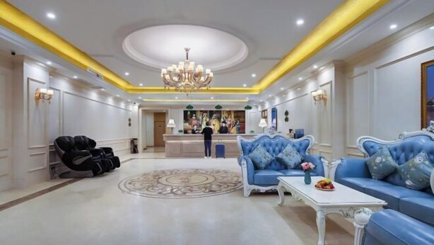A spacious lobby with a reception desk, blue sofas, a white coffee table, and a massage chair. - Vienna Classic Hotel (Nanjing Nanzhan Jiangning Wanda Plaza) (Nanjing)