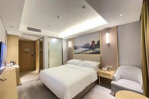 Quarto de hotel com cama, mesa de cabeceira, cadeira e um quadro na parede.
