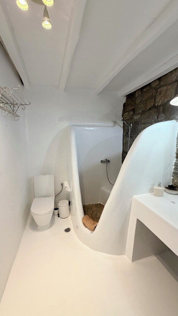 A bathroom with a white toilet, a shower, and a sink.