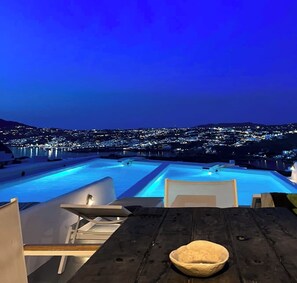 A rooftop pool with a view of a cityscape at night.