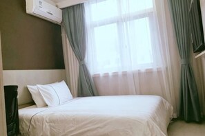 A hotel room with a bed, curtains, and an air conditioning unit. - Qianlixing Inn (Shijiazhuang Siyuan Branch) (Shijiazhuang)