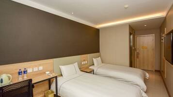 A hotel room with two beds, a desk with a chair, a TV, and a door.