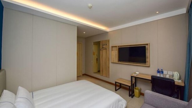A hotel room with a bed, a desk, a chair, a TV, and a mirror. - Qianlixing Inn (Shijiazhuang Siyuan Branch) (Shijiazhuang)