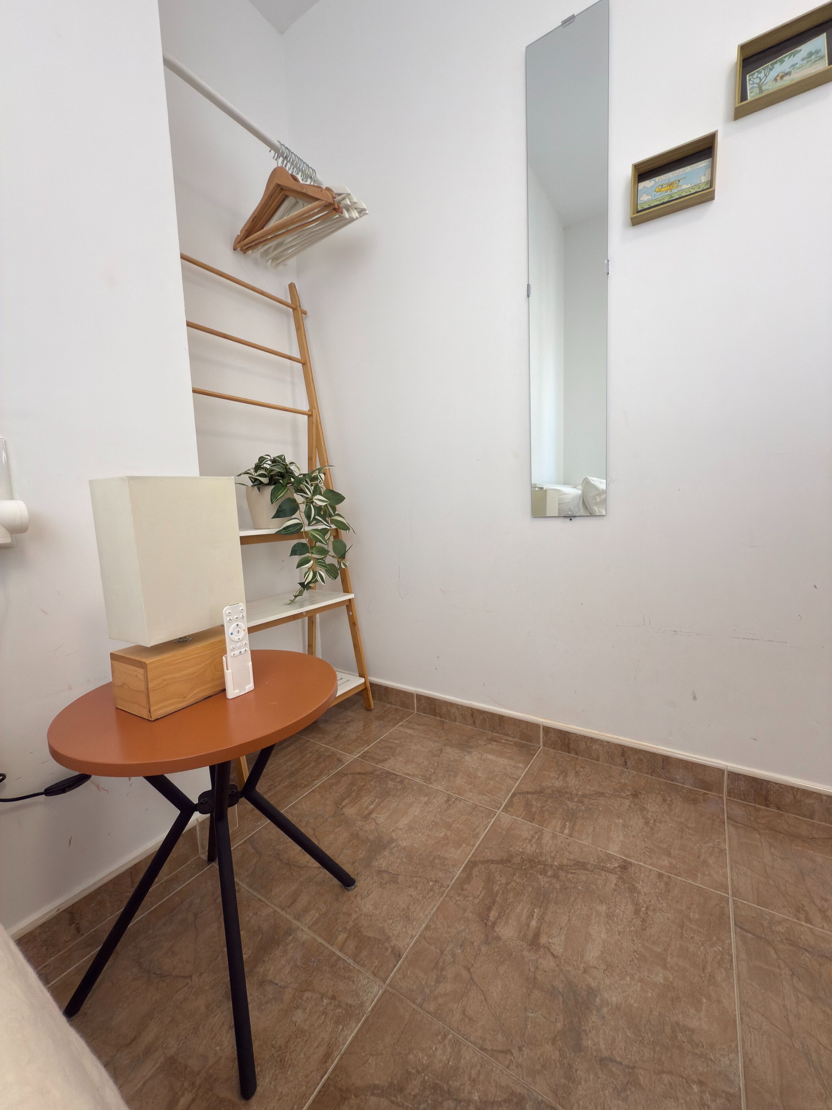 Une petite pièce avec une table en bois, un tableau blanc, une plante et une échelle appuyée contre le mur.