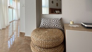A modern room with a woven ottoman, a white console table with a glass candle, and a wall-mounted mirror. - Láttic, Terres de lébre Biosphere Reserve (La Ràpita)