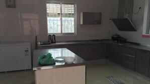 Una cuina amb finestra, armaris, un rentapeus i un frigorífic petit.