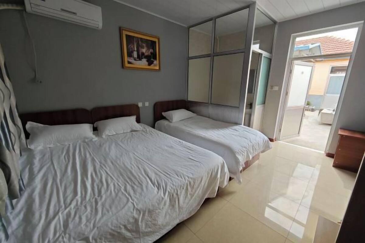 A hotel room with two beds, a large mirror, and a painting on the wall.