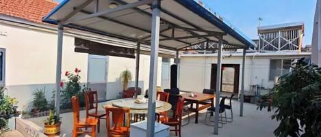 An outdoor patio with a covered seating area, tables, and chairs.