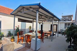 Eine Terrasse im Freien mit überdachter Sitzgelegenheit, Tischen und Stühlen.