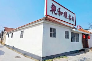 Ein Gebäude mit einem Schild in chinesischen Schriftzeichen, einem Ziegeldach und einem kleinen Eingang.
