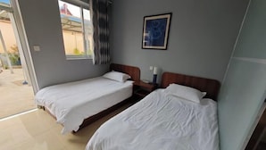 Habitació d'hotel amb dos llits individuals, una taula petita i una finestra amb cortines.