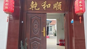 Una porta de fusta amb caràcters xinesos daurats i un emblema decoratiu.