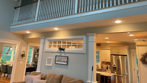 A spacious living area with a high ceiling, a balcony with wooden railings, and a kitchen with stainless steel appliances. - Beautiful, private getaway, close to all New England attractions (Hampton Falls)