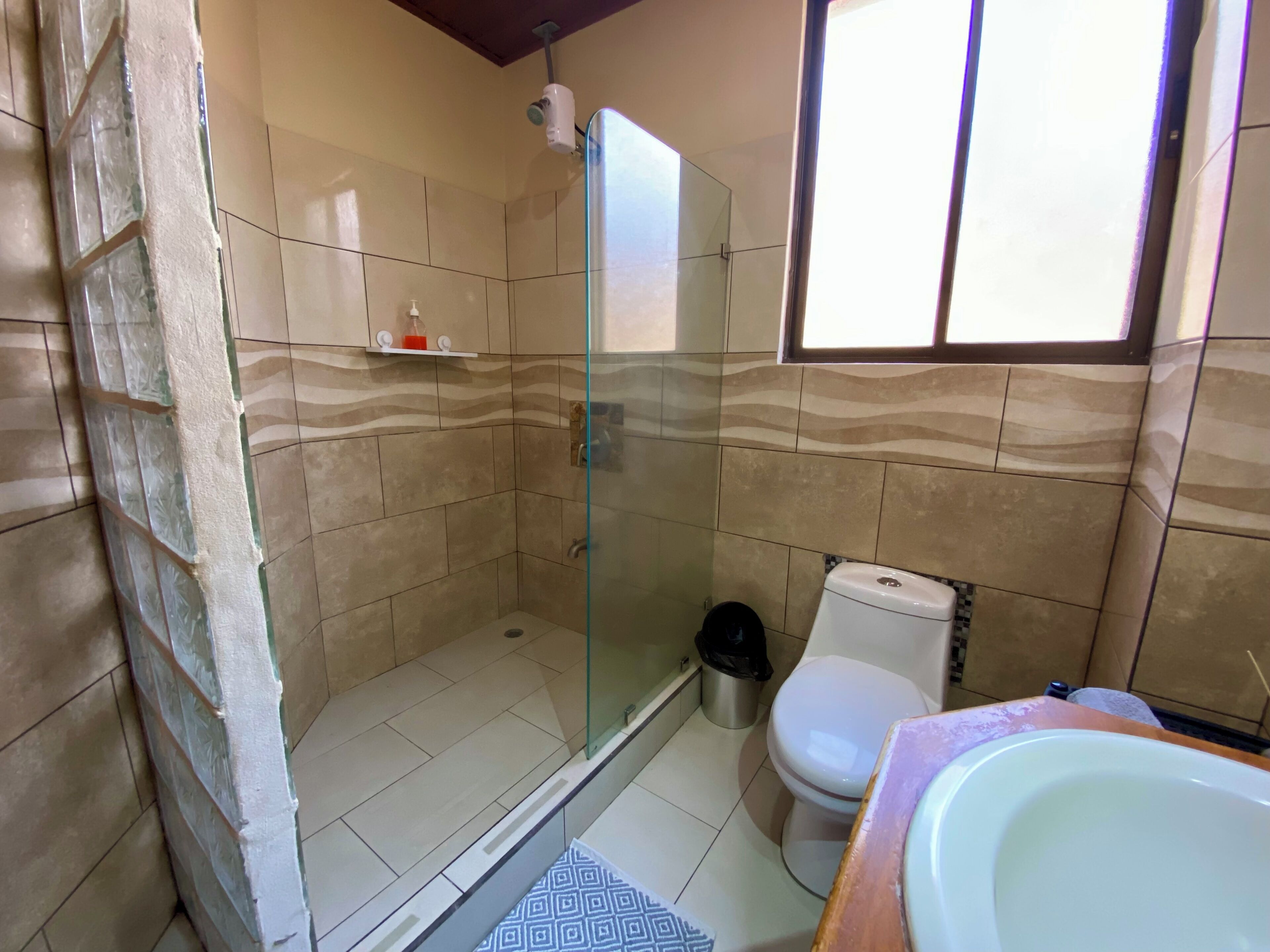 A bathroom with a glass shower enclosure, a toilet, and a sink.