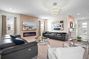 A modern living room with a flat-screen TV, leather sofas, a coffee table, and a fireplace. - 6BD Storey Lake Luxury Villa (SL 4586) (Kissimmee)