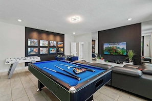 A pool table with billiard balls, a foosball table, and a television displaying a game. - 6BD Storey Lake Luxury Villa (SL 4586) (Kissimmee)