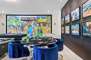 A room with a pool table, blue chairs, and a wall with video game posters. - 6BD Storey Lake Luxury Villa (SL 4586) (Kissimmee)