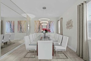 Un comedor moderno con una mesa de vidrio, sillas blancas y un jarrón de flores.