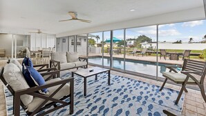 Un amplio espacio interior con piscina, asientos cómodos y ventanas grandes que ofrecen vistas al exterior.