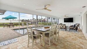 Un patio interior amplio con piscina, comedor y televisor.