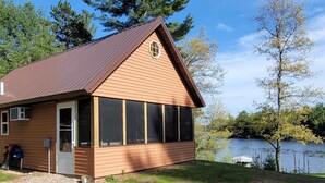 A single-story wooden cabin with a brown roof, large windows, and a door. - Lakefront Lodging, Beach, Fire Pit, Bar & Grill, Rentals, Live Music, Trails (Tomahawk)